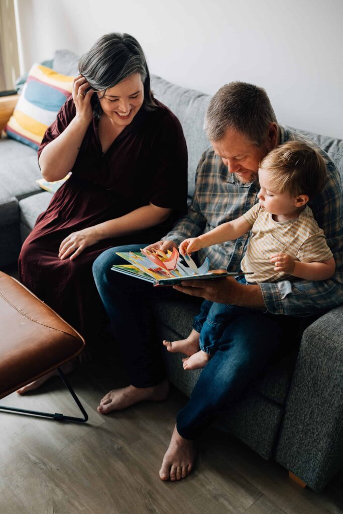 Mum, Dad and son sit on couch reading a book, value of photography, especially plus size family photos