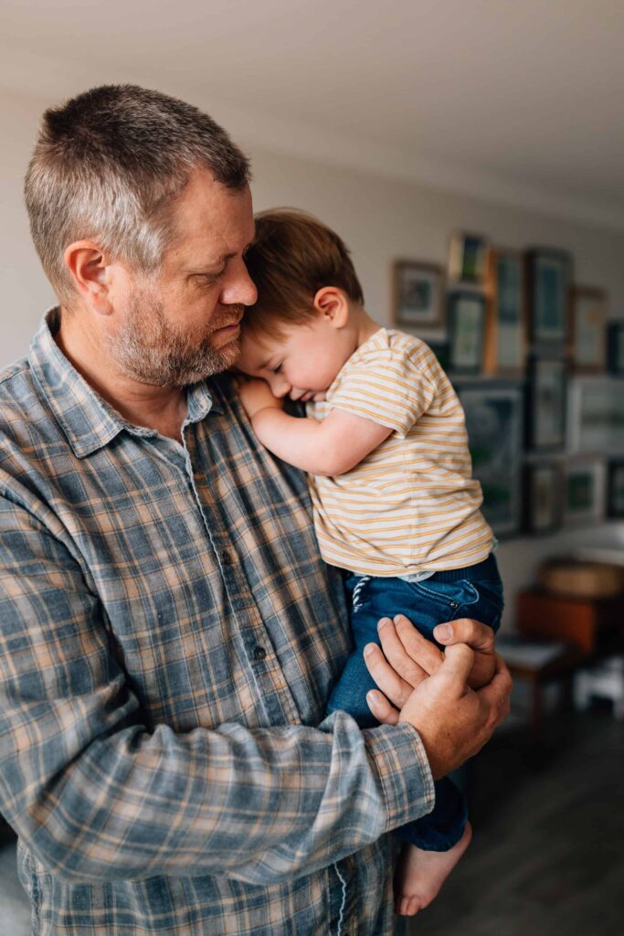 boy snuggled in, held in dad's arms, value of photography, especially plus size family photos