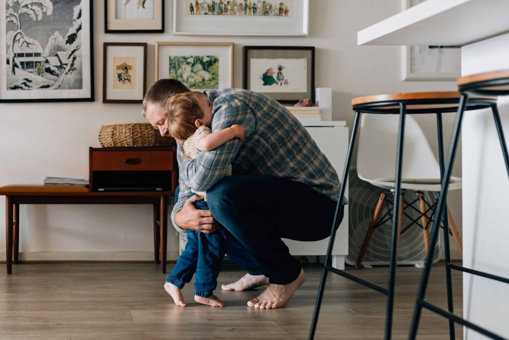 Dad crouched down as boy hugs him, value of photography, especially plus size family photos