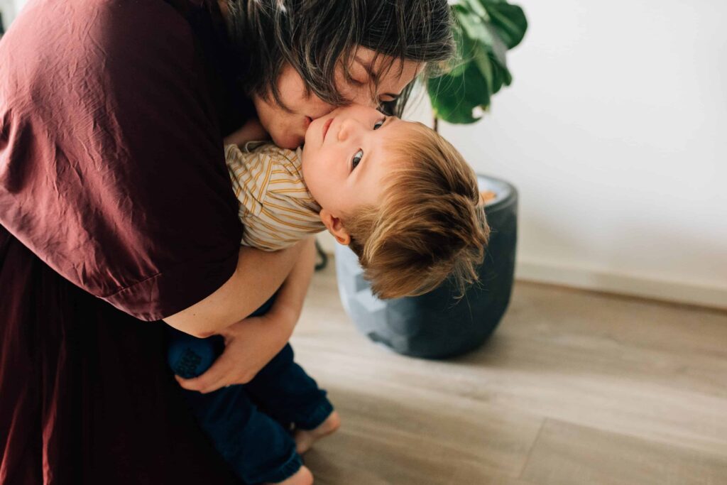 boy bent backwards as Mum hugs and kisses him, value of photography, especially plus size family photos