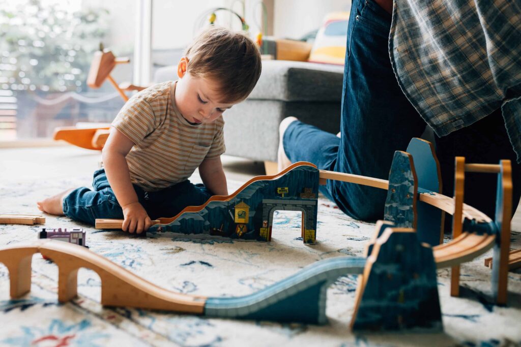 Boy sitting on floor playing with train set, value of photography, especially plus size family photos