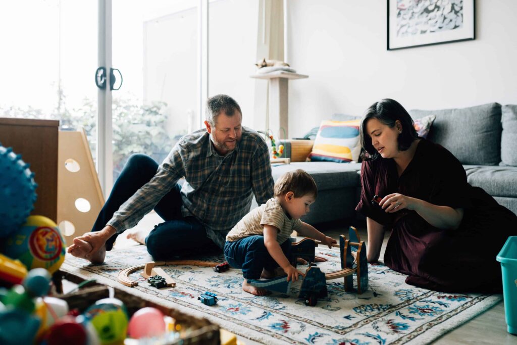 Mum, Dad and boy sitting on floor playing with toy trains, value of photography, especially plus size family photos